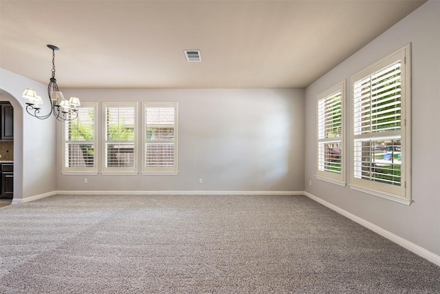 empty room with carpet floors and an inviting chandelier