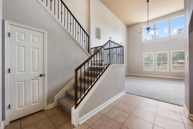 stairs with a high ceiling, carpet floors, and ceiling fan