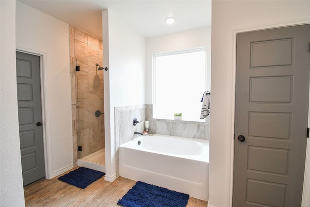 bathroom with shower with separate bathtub and wood-type flooring