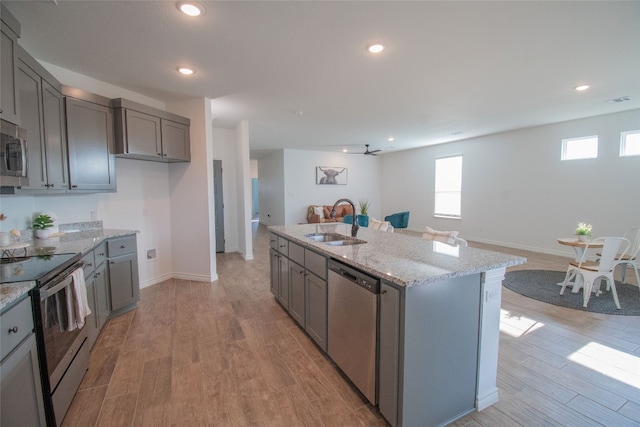 kitchen featuring light wood-type flooring, a center island with sink, appliances with stainless steel finishes, and sink