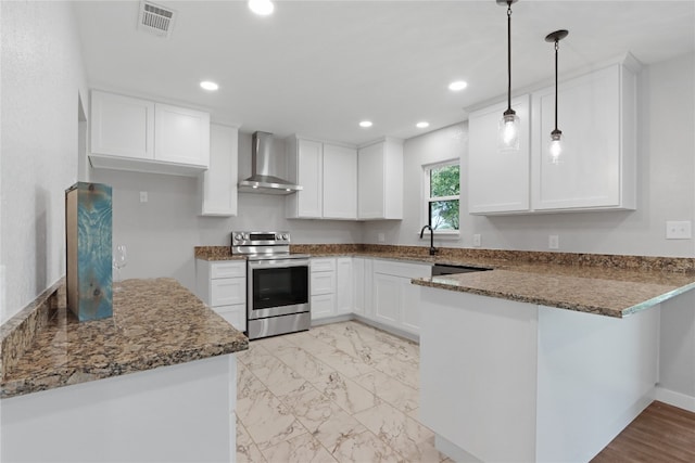 kitchen with electric range oven, hanging light fixtures, light hardwood / wood-style floors, dark stone countertops, and wall chimney exhaust hood