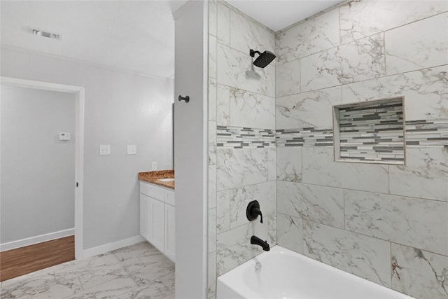 bathroom with hardwood / wood-style flooring, tiled shower / bath combo, and vanity