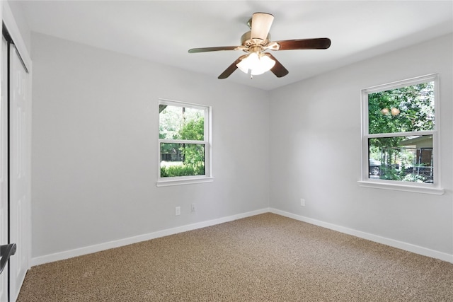 empty room with carpet flooring, a wealth of natural light, and ceiling fan