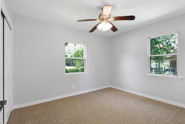 carpeted spare room with baseboards and a ceiling fan
