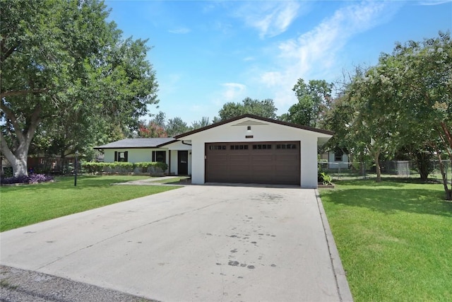 ranch-style house with fence, an attached garage, stucco siding, a front lawn, and driveway