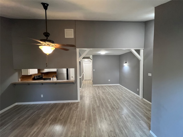 unfurnished living room featuring sink, wood-type flooring, and ceiling fan