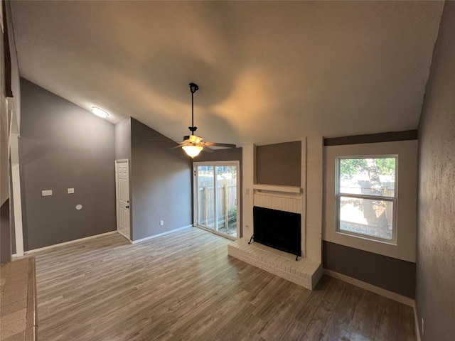 unfurnished living room featuring a brick fireplace, lofted ceiling, hardwood / wood-style flooring, and ceiling fan