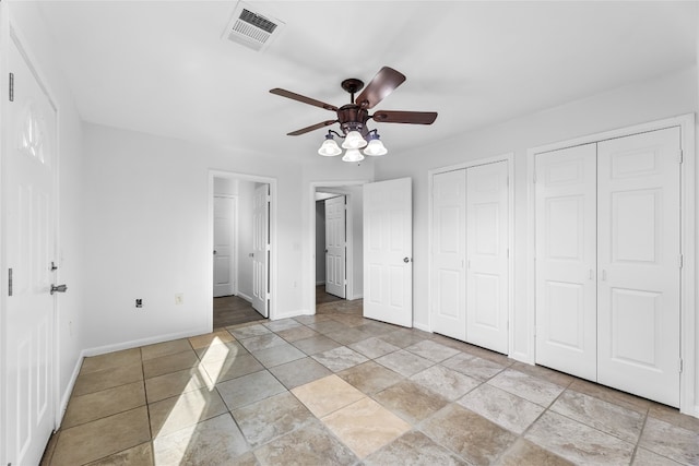 unfurnished bedroom featuring ceiling fan and two closets