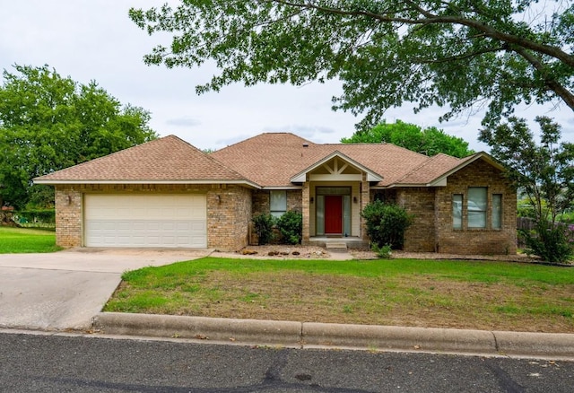 view of front of house with an attached garage, a front lawn, driveway, and brick siding