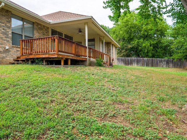 view of yard with a deck, fence, and a ceiling fan
