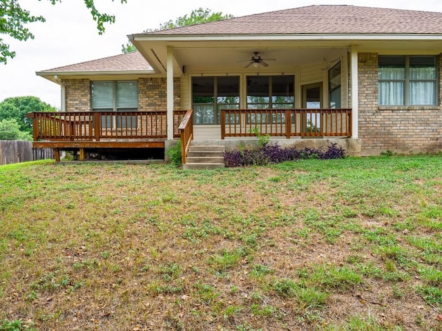 back of property with a lawn, a ceiling fan, roof with shingles, and brick siding