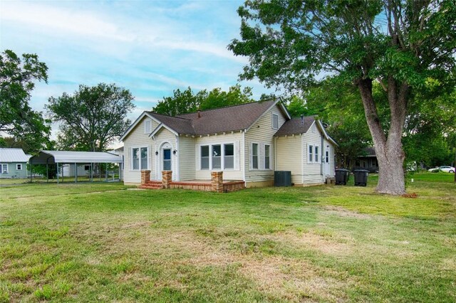 rear view of property featuring a carport, cooling unit, and a yard