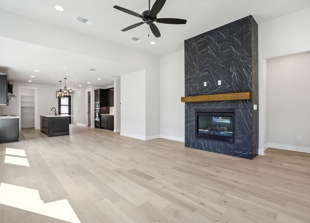 151 William Hersee Dr, Bastrop, TX 78602 - unfurnished living room with light wood-type flooring, a fireplace, a ceiling fan, baseboards, and recessed lighting