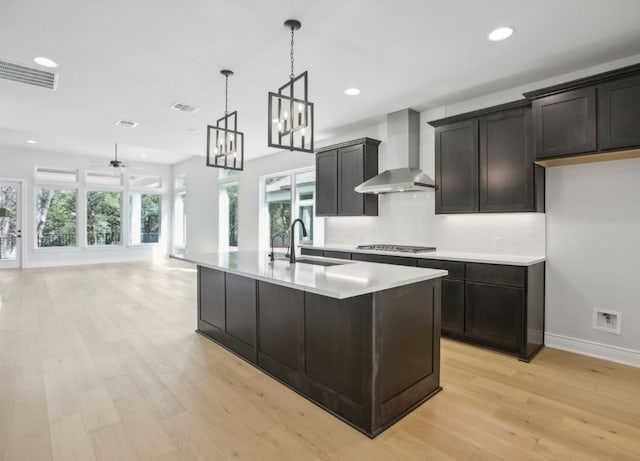 kitchen featuring light hardwood / wood-style flooring, a healthy amount of sunlight, wall chimney range hood, and stainless steel gas stovetop