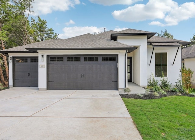 prairie-style home with a garage and a front lawn