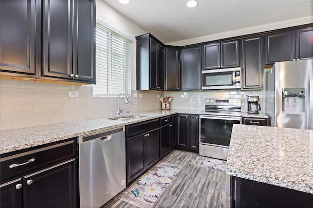 kitchen featuring appliances with stainless steel finishes, tasteful backsplash, light stone counters, and sink