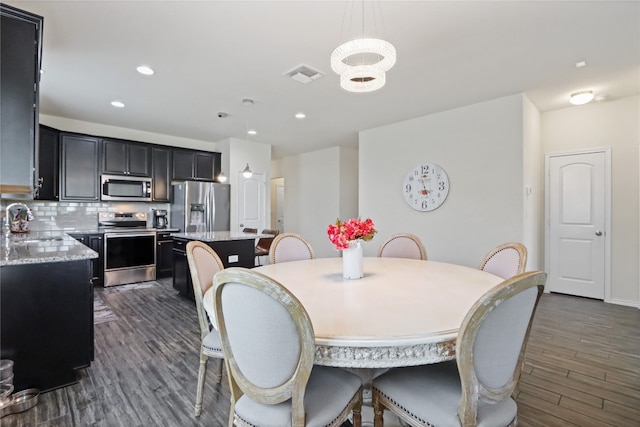 dining room with sink, dark wood-type flooring, and a notable chandelier