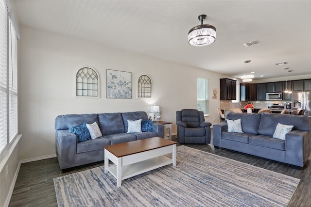 living room with dark hardwood / wood-style flooring, plenty of natural light, and a chandelier