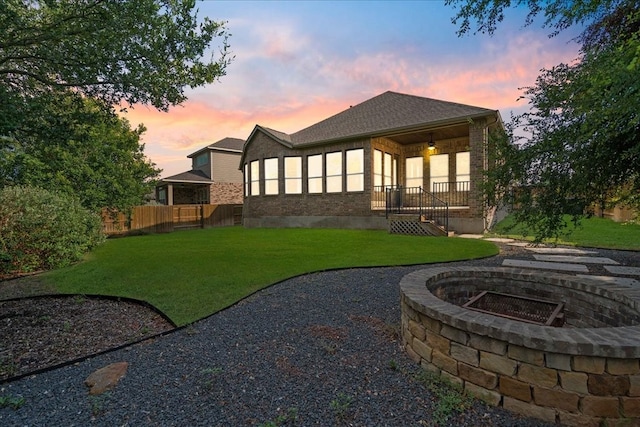 back house at dusk with a lawn and a fire pit