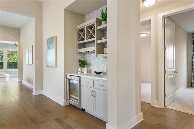 bar with dark hardwood / wood-style floors, wine cooler, and backsplash