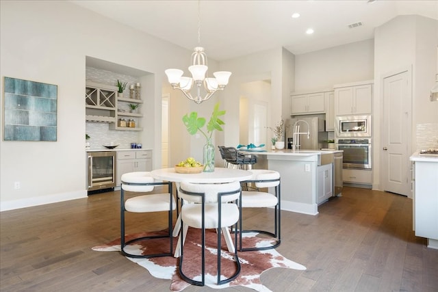 dining room with a towering ceiling, an inviting chandelier, dark hardwood / wood-style floors, and wine cooler