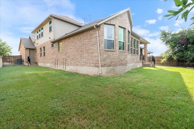 view of side of property with central AC unit and a yard