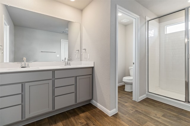 bathroom featuring a shower with shower door, toilet, wood-type flooring, and dual bowl vanity