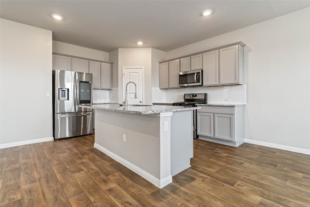 kitchen featuring sink, dark hardwood / wood-style floors, stainless steel appliances, and an island with sink