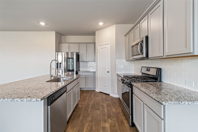 kitchen with stainless steel appliances, decorative backsplash, sink, dark hardwood / wood-style floors, and a kitchen island with sink