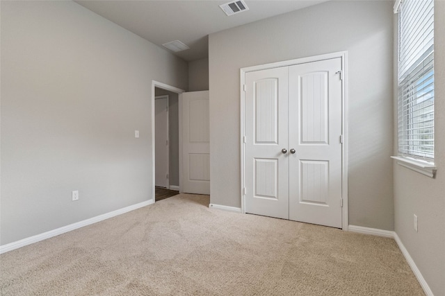 unfurnished bedroom featuring a closet and light colored carpet