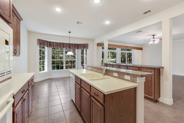 kitchen with light tile patterned flooring, sink, pendant lighting, and a center island with sink