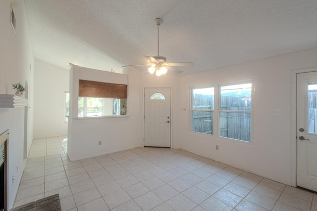 foyer entrance featuring light tile patterned flooring, ceiling fan, lofted ceiling, and a textured ceiling