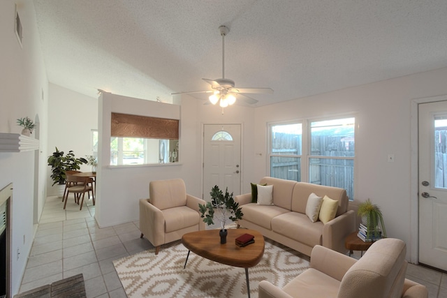 tiled living room with ceiling fan, lofted ceiling, and a textured ceiling