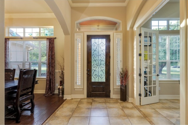 foyer entrance featuring french doors, ornamental molding, and light wood-type flooring