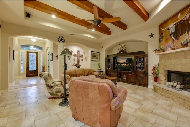 tiled living room featuring ceiling fan, beam ceiling, and a fireplace