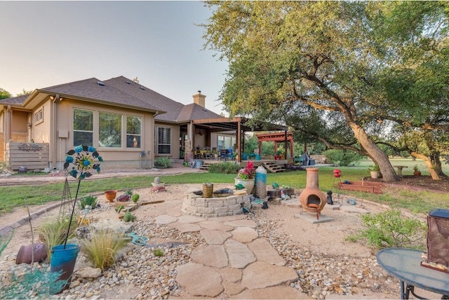 back house at dusk featuring a fire pit, a patio area, and a pergola