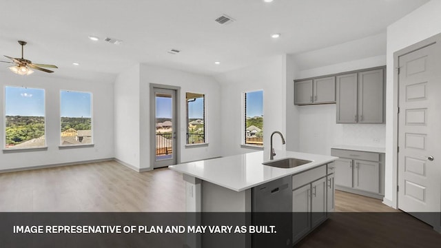 kitchen featuring gray cabinets, tasteful backsplash, a kitchen island with sink, light wood-type flooring, and sink