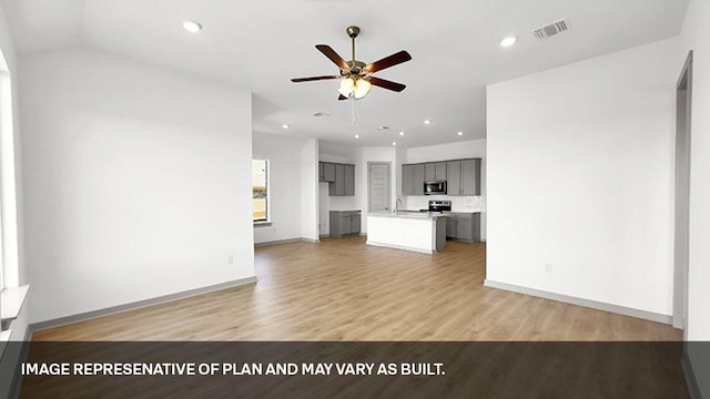 unfurnished living room with light hardwood / wood-style floors, sink, lofted ceiling, and ceiling fan