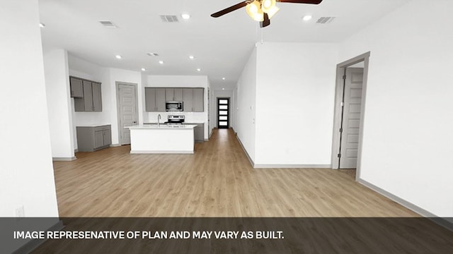 kitchen with light hardwood / wood-style floors, ceiling fan, appliances with stainless steel finishes, gray cabinetry, and a kitchen island with sink