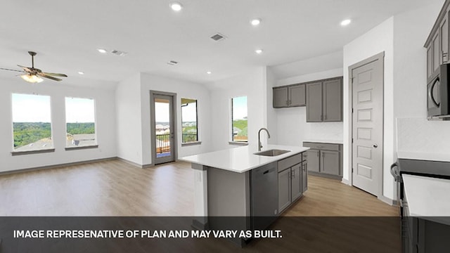 kitchen featuring dishwasher, sink, light hardwood / wood-style flooring, a kitchen island with sink, and gray cabinetry