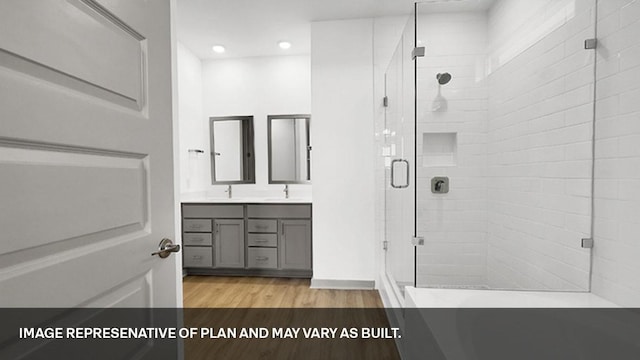 bathroom with walk in shower, vanity, and hardwood / wood-style floors