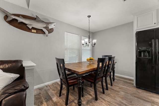 dining space with wood-type flooring and an inviting chandelier