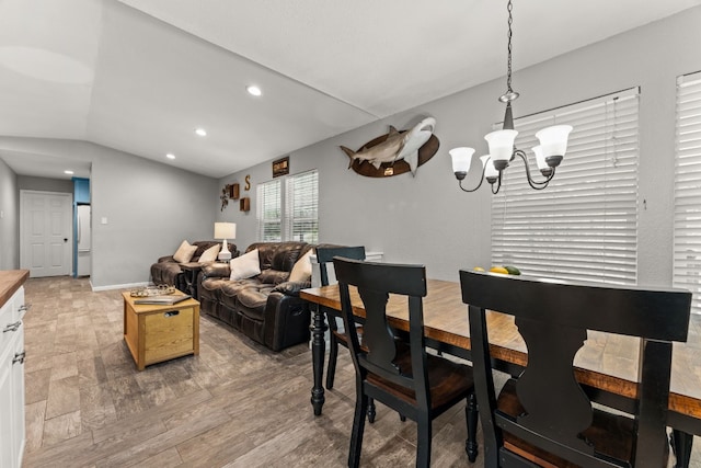 dining area featuring vaulted ceiling, an inviting chandelier, and hardwood / wood-style floors