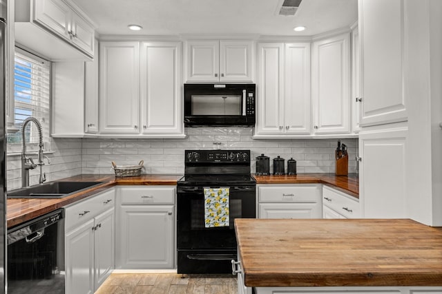 kitchen featuring white cabinets, black appliances, sink, and butcher block counters