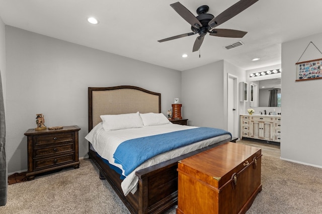 bedroom with light carpet, ensuite bath, and ceiling fan