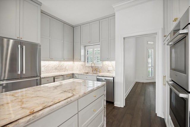 kitchen with sink, light stone counters, dark hardwood / wood-style floors, and stainless steel appliances