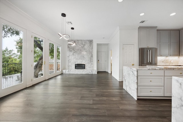 kitchen featuring light stone countertops, a high end fireplace, dark wood-type flooring, hanging light fixtures, and high end fridge