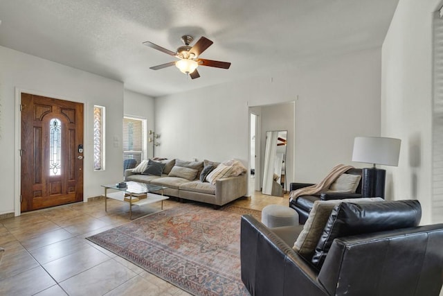 living area featuring tile patterned flooring, ceiling fan, and a textured ceiling