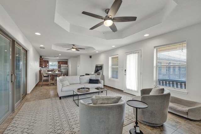 living room with ceiling fan, a tray ceiling, and recessed lighting