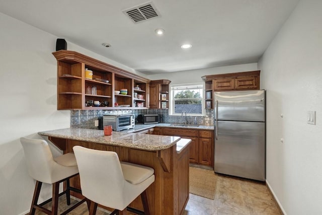 kitchen with visible vents, decorative backsplash, stainless steel appliances, open shelves, and a sink